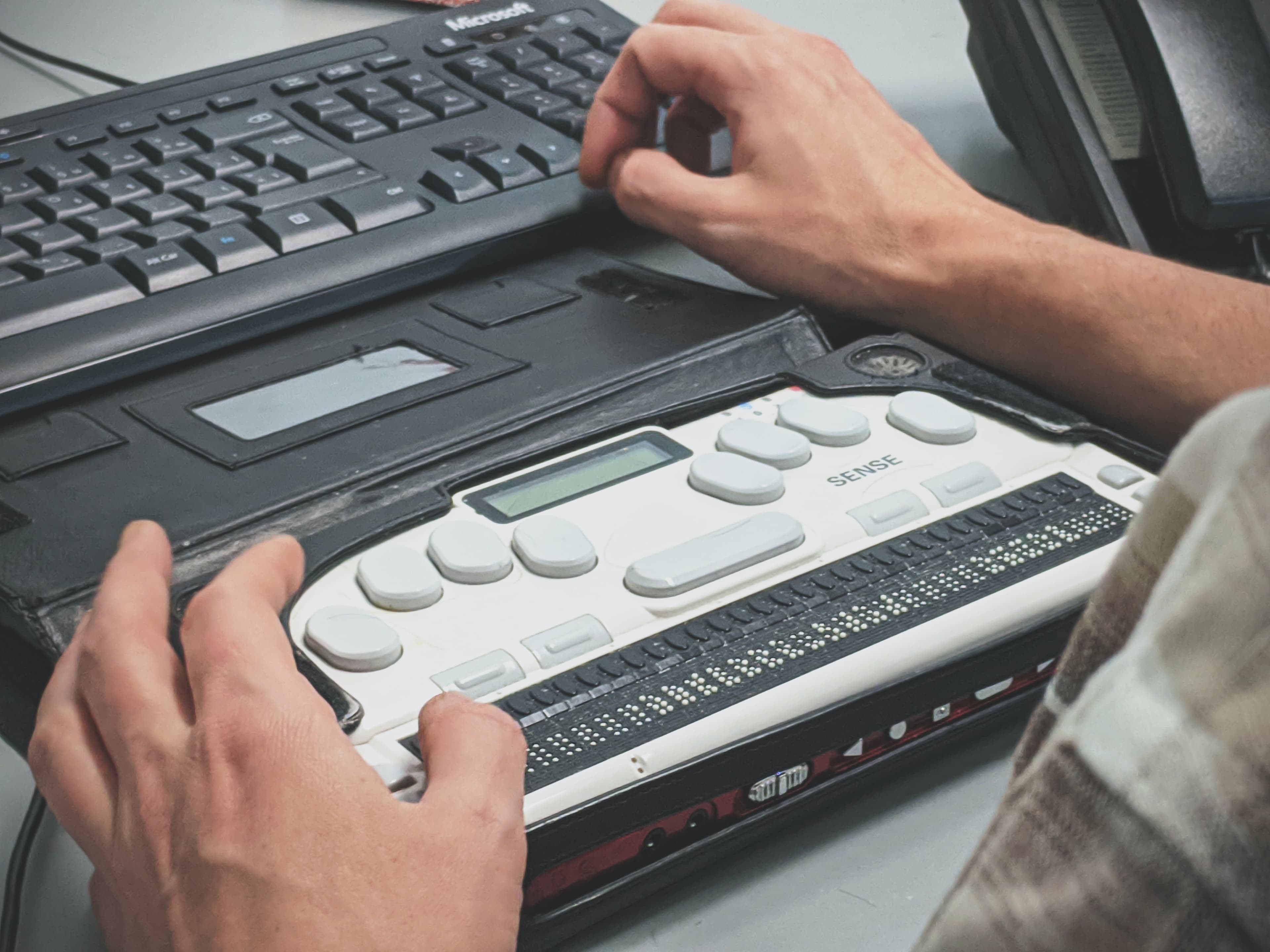 A person using a computer with a refreshable braille display